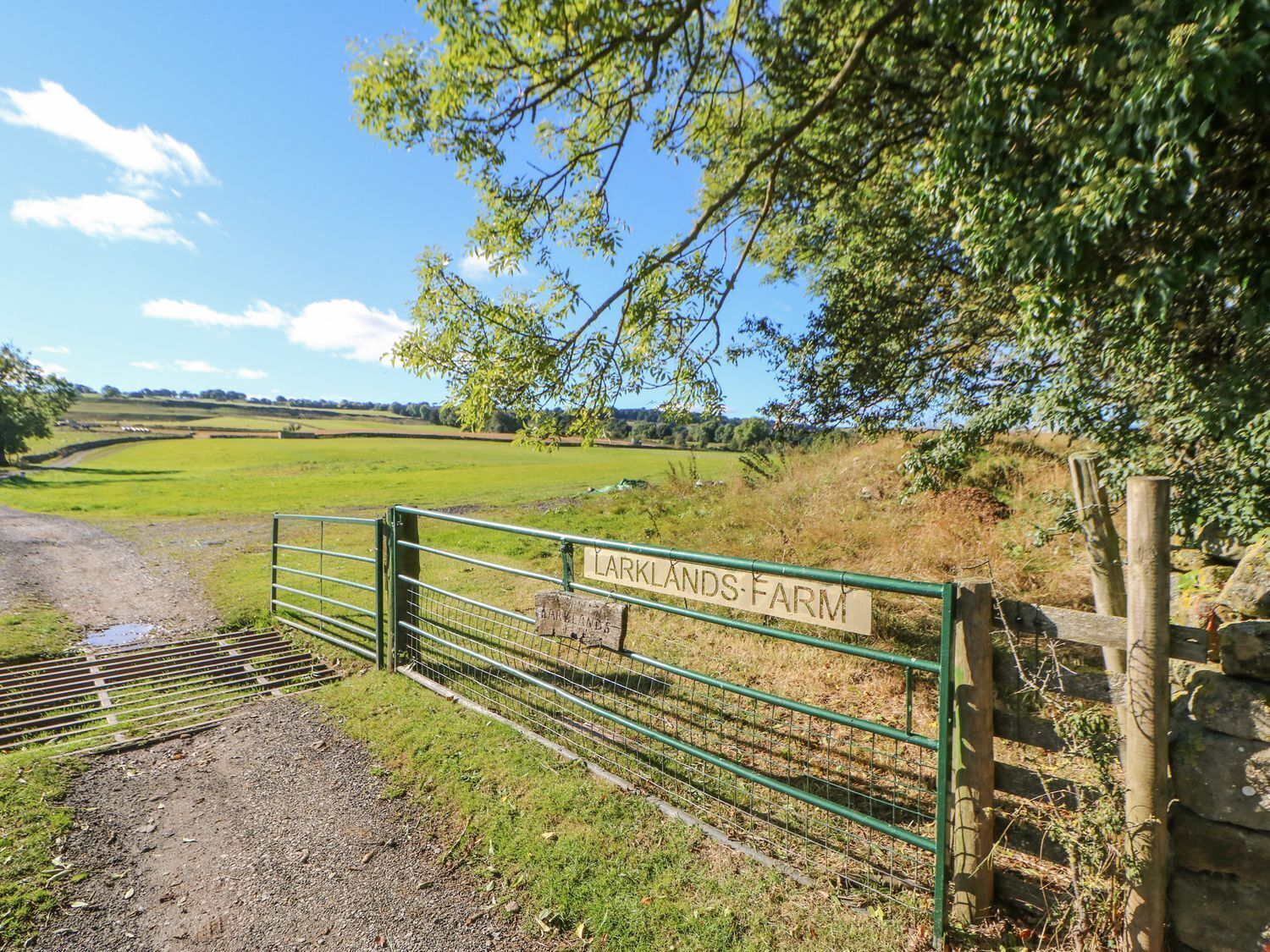 A rural farm entrance with a metal gate and a sign reading "Larklands Farm".