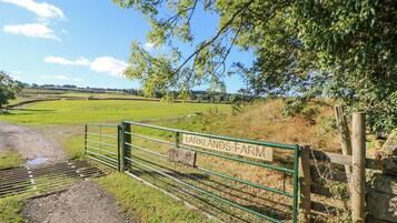 A rural farm entrance with a metal gate and a sign reading "Larklands Farm".