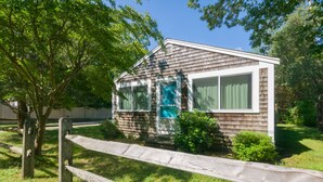 Une petite maison de plain-pied avec un porche à l’avant et une clôture en bois.