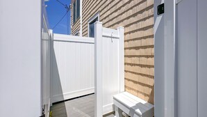 Una terraza de madera blanca con un banco, una cerca blanca y un edificio con revestimiento horizontal.