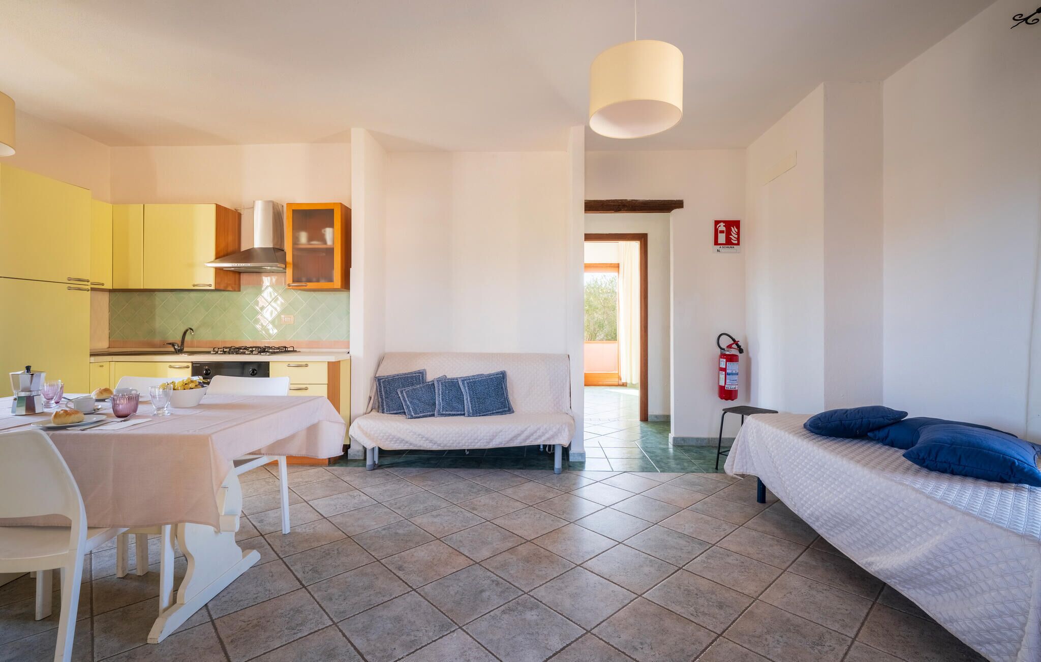 Habitació compacta amb cuina americana, zona de menjador i llit.