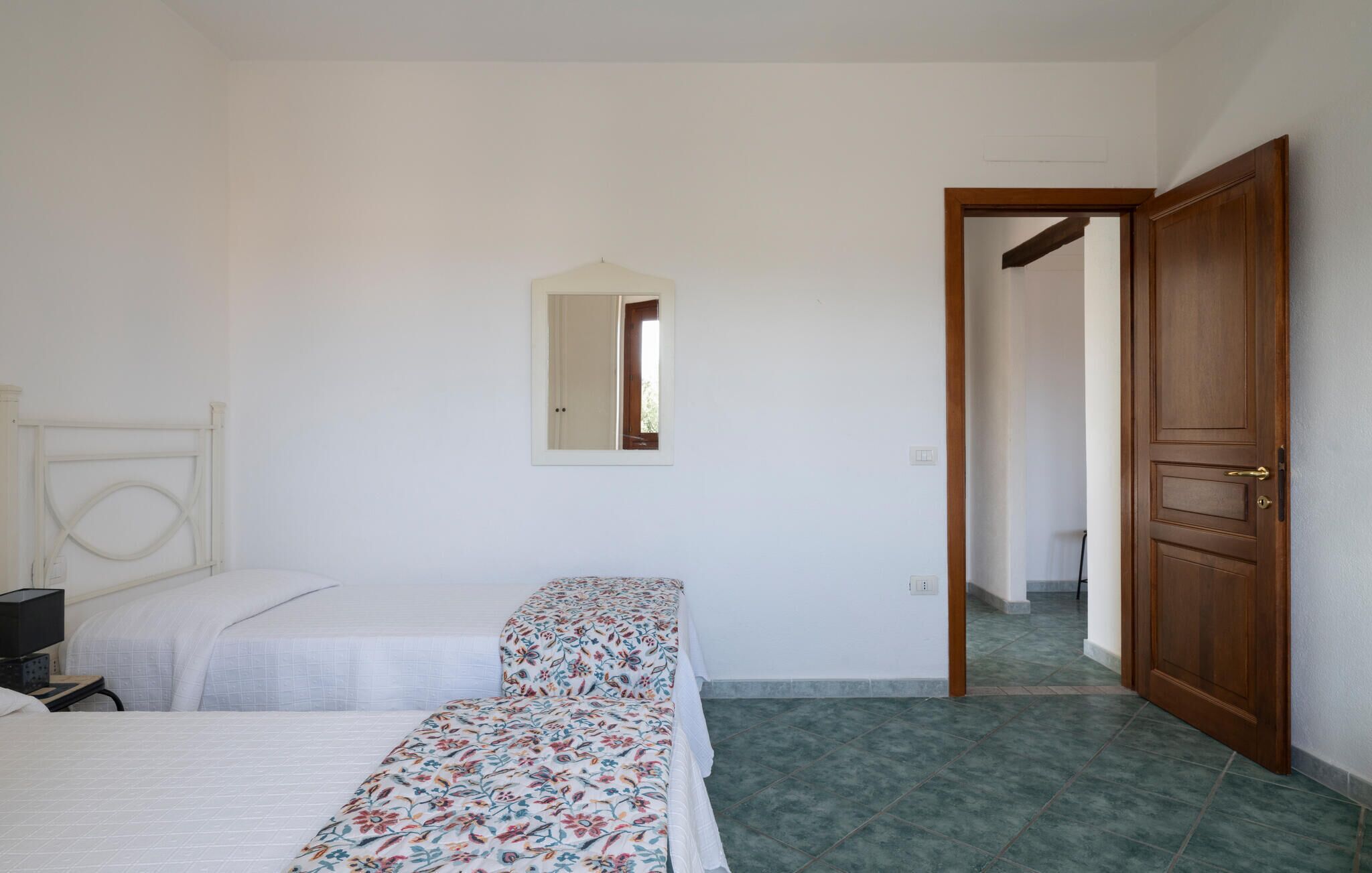 Een slaapkamer met twee bedden, een houten deur en een spiegel aan de muur.