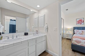 Une salle de bain moderne avec deux lavabos, un grand miroir et un dressing.