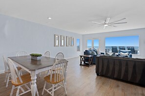 Un vaste espace de vie comprenant une table à manger, des chaises, un canapé et un ventilateur de plafond.