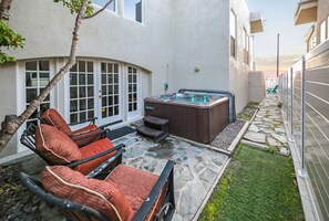 Une terrasse avec des sièges extérieurs, un jacuzzi et un chemin en pierre.