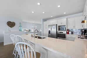 A modern kitchen with white cabinetry, stainless steel appliances, and a central island with seating.