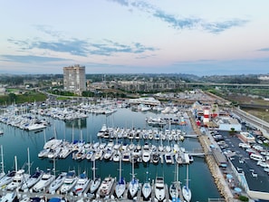Un port de plaisance où sont amarrés de nombreux bateaux, un pont en arrière-plan et une vue sur la ville côtière.