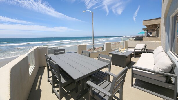 Een balkon met uitzicht op de oceaan, een tafel, stoelen en een bank.