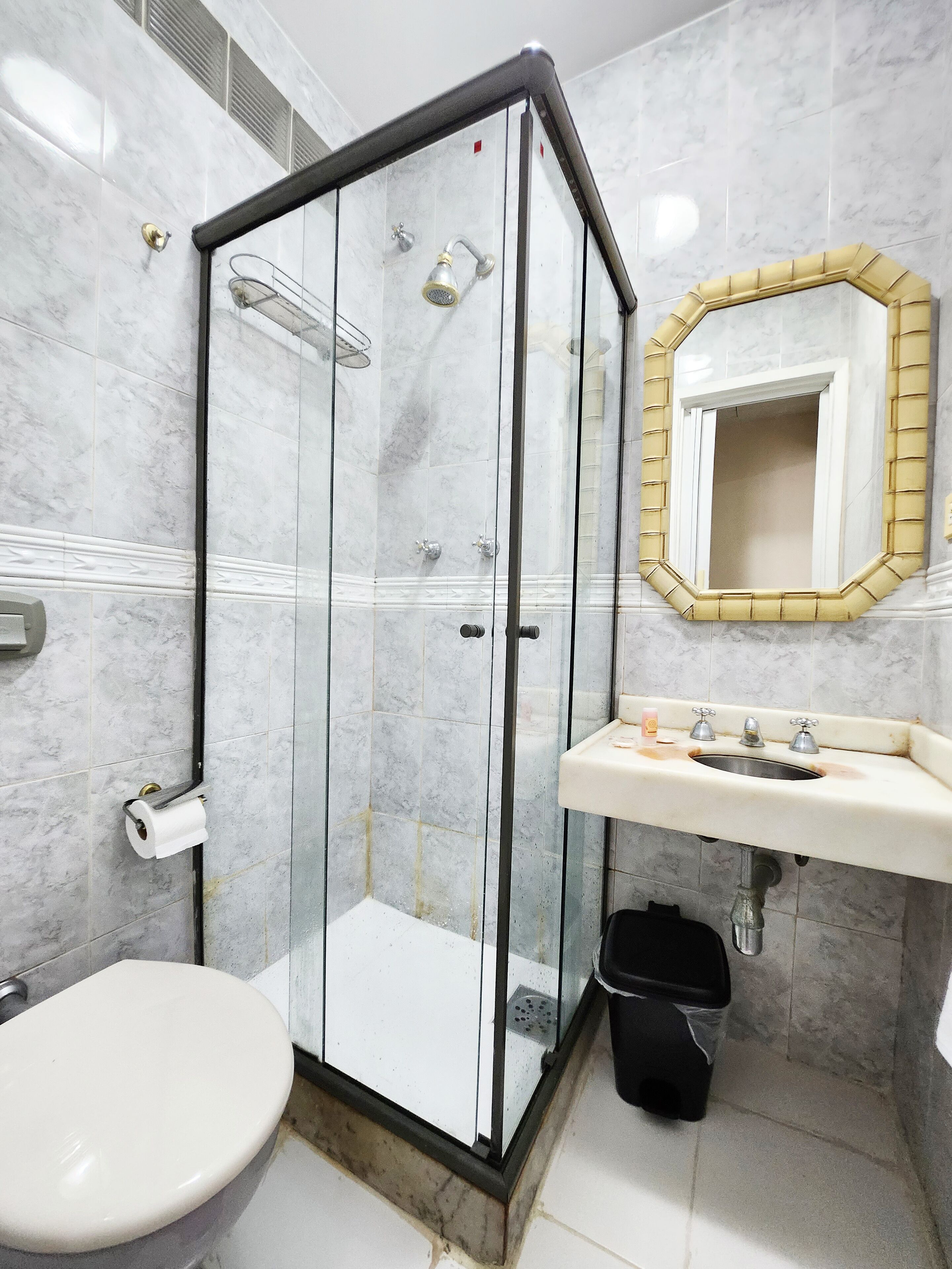 A bathroom with a glass-enclosed shower, a white sink with a mirror, and a toilet.
