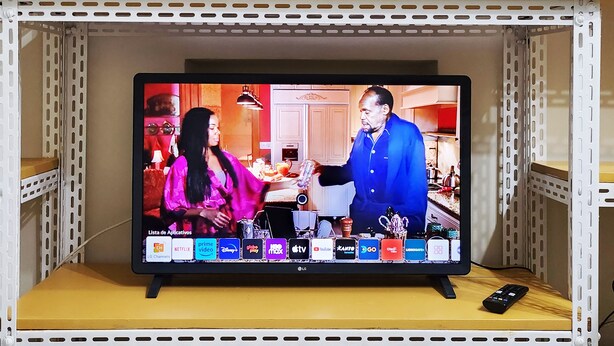 A television on a shelf displaying a scene with two people in a kitchen. - Leblon Comfort Suite (Rio de Janeiro)