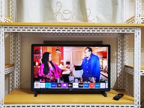 A television on a shelf displaying a scene with two people in a kitchen. - Leblon Comfort Suite (Rio de Janeiro)