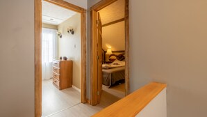 A hallway with a wooden bench, a dresser, and a bed in the adjacent room. - Rustic Villa | 3 Bedrooms, Fireplace, Pet-Friendly & Near Lac Maskinongé (Saint-Gabriel-de-Brandon)