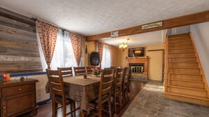 A dining area with a wooden table and chairs, a fireplace, and a staircase. - Rustic Villa | 3 Bedrooms, Fireplace, Pet-Friendly & Near Lac Maskinongé (Saint-Gabriel-de-Brandon)
