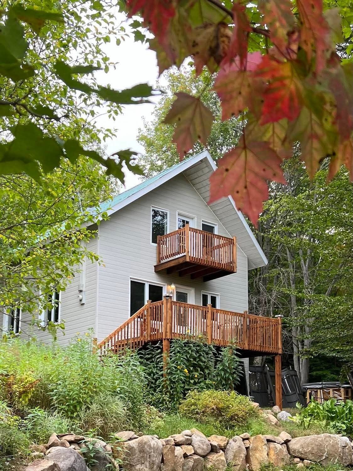 A two-story house with a wooden deck and a stone wall in front.