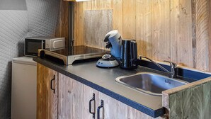A compact kitchen with a microwave, coffee maker, and sink.