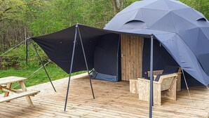 A large tent with a wooden deck and picnic table.
