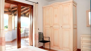 Ein Schlafzimmer mit Bett, Kleiderschrank und Stuhl. Ein Balkon mit Tisch und Stühlen ist vorhanden.