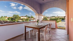 A balcony with a table and chairs, a bottle of wine, and a glass. - 1 bedroom beautiful apartment in San Teodoro (San Teodoro)