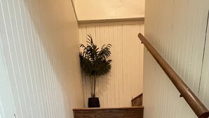 Een houten trap met witte paneelwanden.