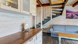Un interior de madera con una encimera de cocina, un sofá y una escalera.