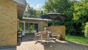 A patio with a table and chairs, a brick wall, and a large umbrella. - 3 bedroom lovely home in Hurup Thy (Hurup Thy)