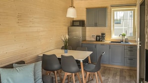 A compact kitchen with a refrigerator, microwave, and coffee maker. There is a dining table with four chairs and a potted plant. - 2 bedroom cozy home in Debki (Debki)