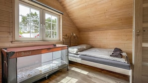 A small, wooden cabin bedroom with two bunk beds, a window with a view of trees, and a door. - 2 bedroom cozy home in Debki (Debki)
