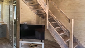 A wooden interior with a staircase, a television on a stand, and a door leading to another room. - 2 bedroom cozy home in Debki (Debki)