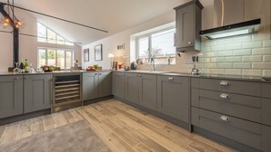 A modern kitchen with grey cabinets, a built-in oven, and a large window providing natural light. - Weavers, Felbrigg, Norfolk (Felbrigg)