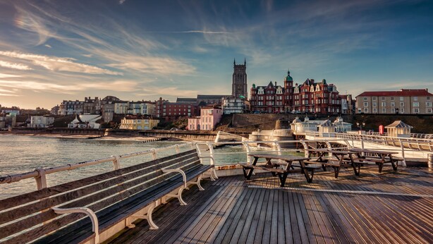 A wooden pier with benches, a waterfront view, and historic buildings in the background. - Weavers, Felbrigg, Norfolk (Felbrigg)