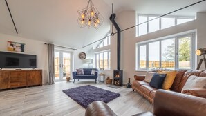 A spacious living room with a fireplace, leather sofas, a large TV, and a modern chandelier. - Weavers, Felbrigg, Norfolk (Felbrigg)