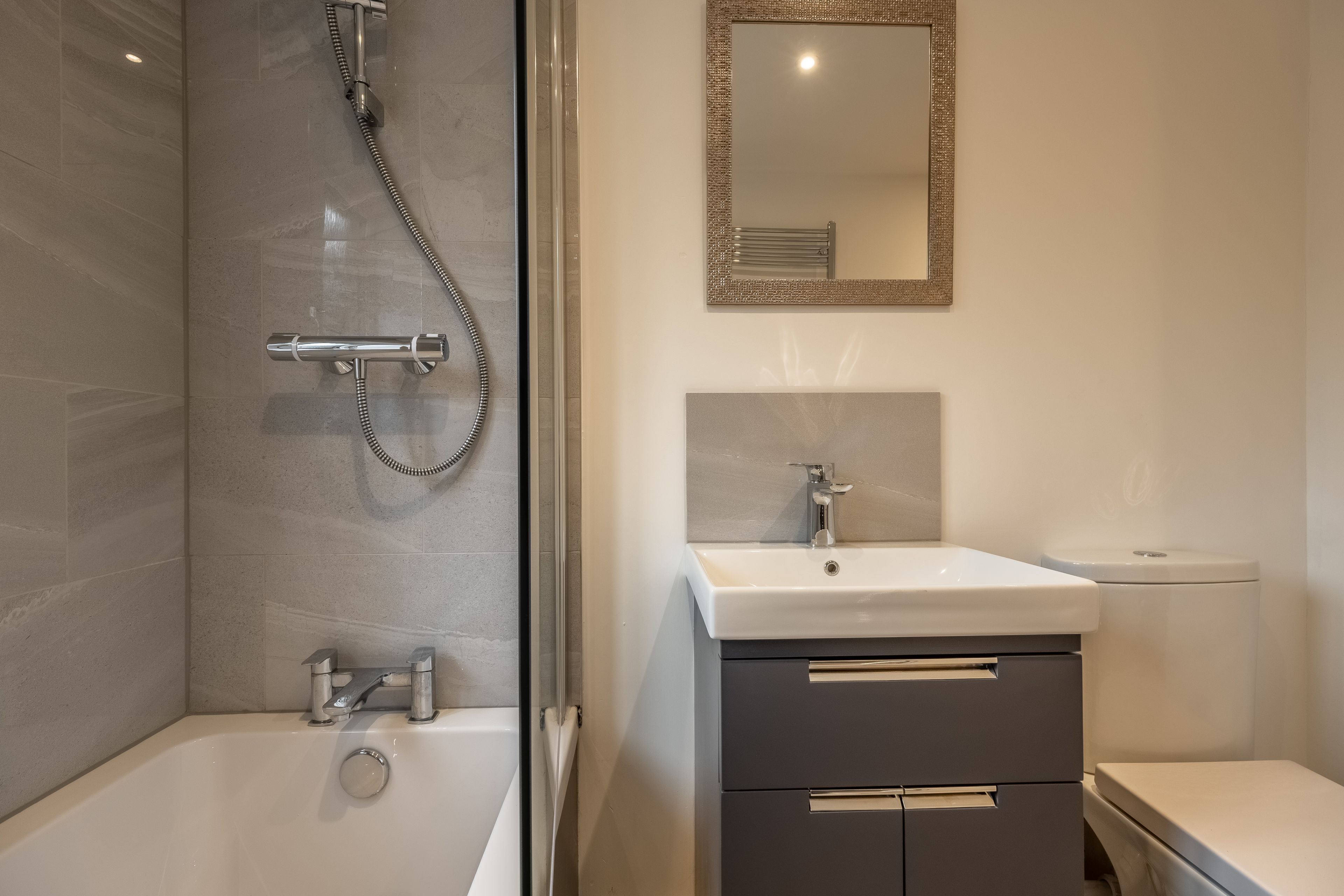 Ein modernes Badezimmer mit einer Duschkabine aus Glas, einem weißen Waschbecken und einer Toilette.