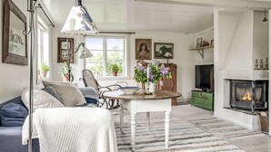 A cozy living room with a sofa, a table with a vase of flowers, a fireplace, and a television. - 4 bedroom cozy home in Ellös (Ellös)