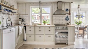 A kitchen with white cabinetry, a built-in oven, and a window with a view of a house. - 4 bedroom cozy home in Ellös (Ellös)