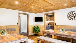 A wooden dining area with a large table, benches, a potted plant, and a wall-mounted clock. - Apartment Catrin – Hochzillertal/Hochfügen Ski Area, Sauna, EV Charging, Mountain Views (Ried im Zillertal)
