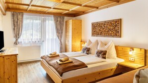 A wooden-framed bedroom with a bed, bedside tables, a radiator, and a wall-mounted artwork. - Apartment Catrin – Hochzillertal/Hochfügen Ski Area, Sauna, EV Charging, Mountain Views (Ried im Zillertal)