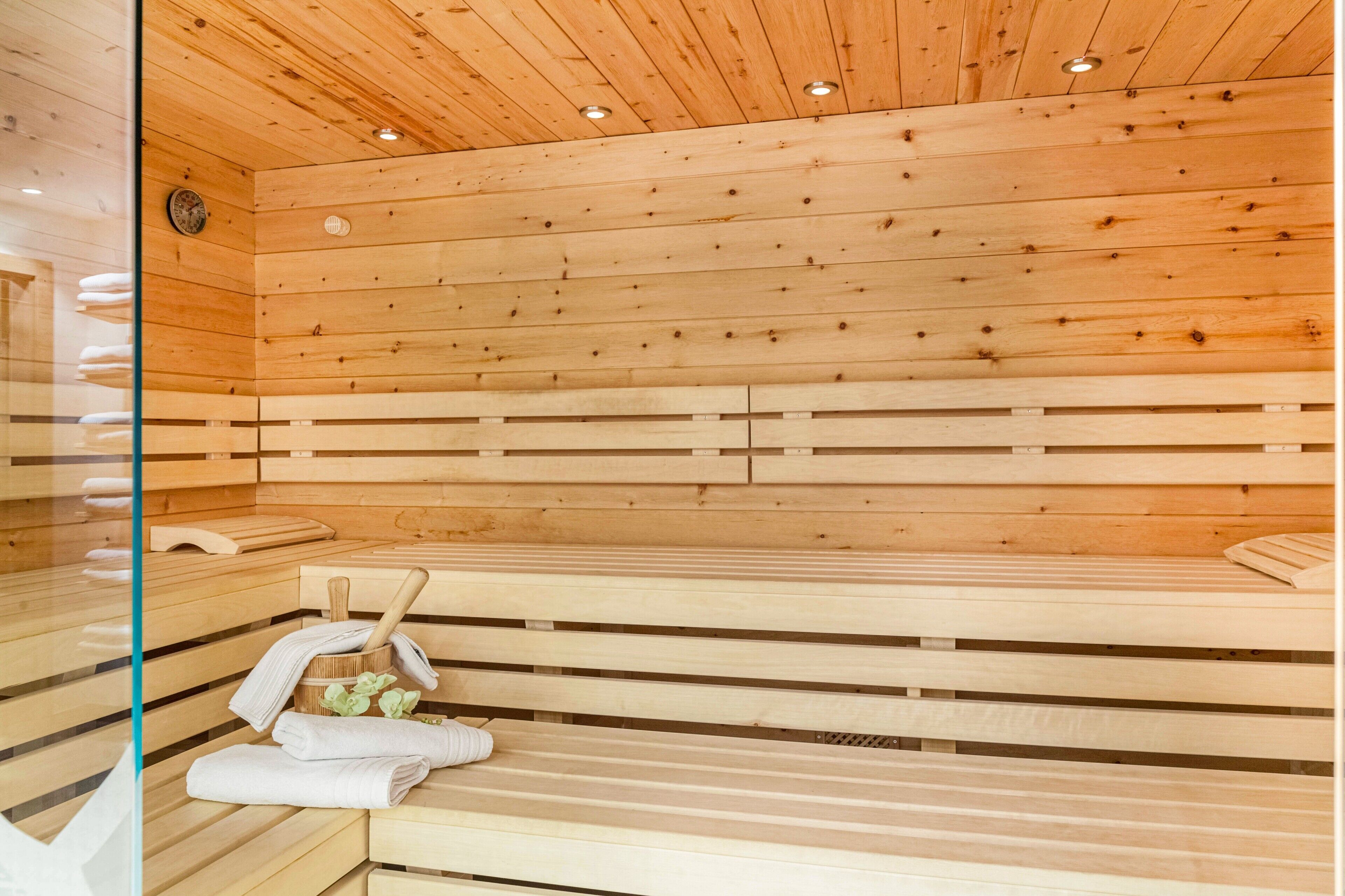 Een sauna met houten banken, een houten plafond en een glazen wand.