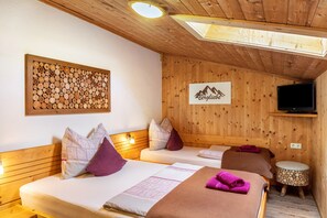 Eine Holzhütte mit zwei Betten, einem an der Wand befestigten Fernseher und einer Wanddekoration aus Baumstämmen.