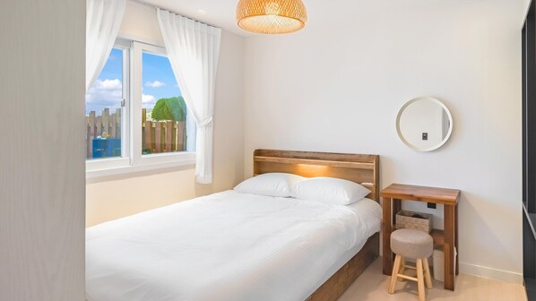 Une chambre à coucher avec un lit, une table de chevet, un miroir et une fenêtre avec des rideaux.