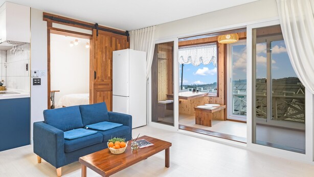 Una sala moderna con un sofá azul, una mesa de centro de madera y vistas a un balcón con comedor.