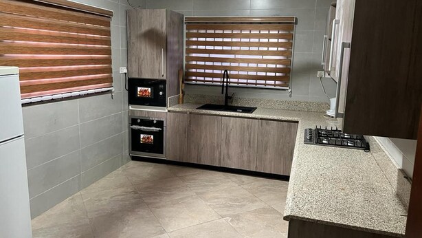 Een kleine keuken met een inbouwoven, magnetron en gasfornuis.