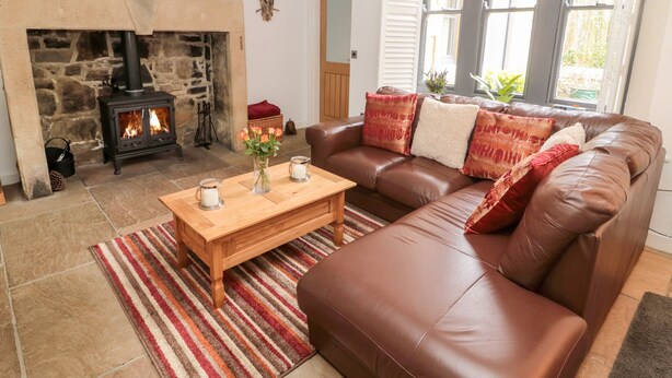 A cozy living room with a stone fireplace, a leather sofa, and a wooden coffee table.