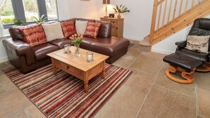 A living room with a brown leather sofa, a wooden coffee table, and a striped rug.