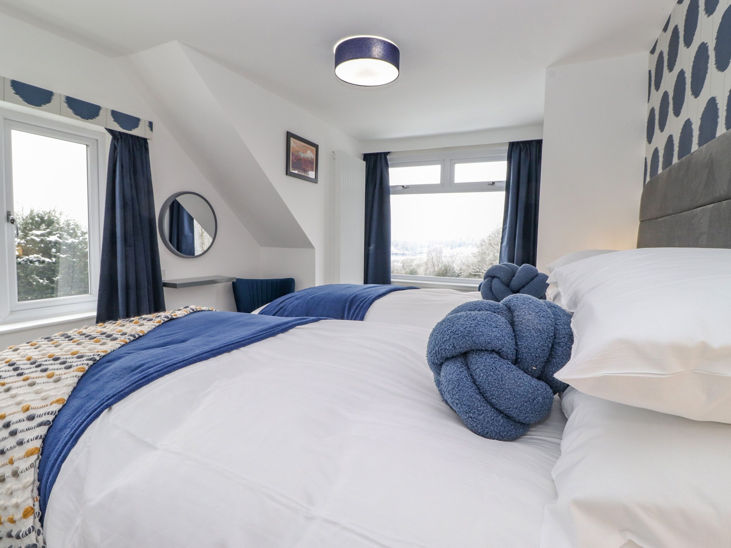 Et moderne hotelværelse med to senge, et stort vindue og udsigt til det fri.