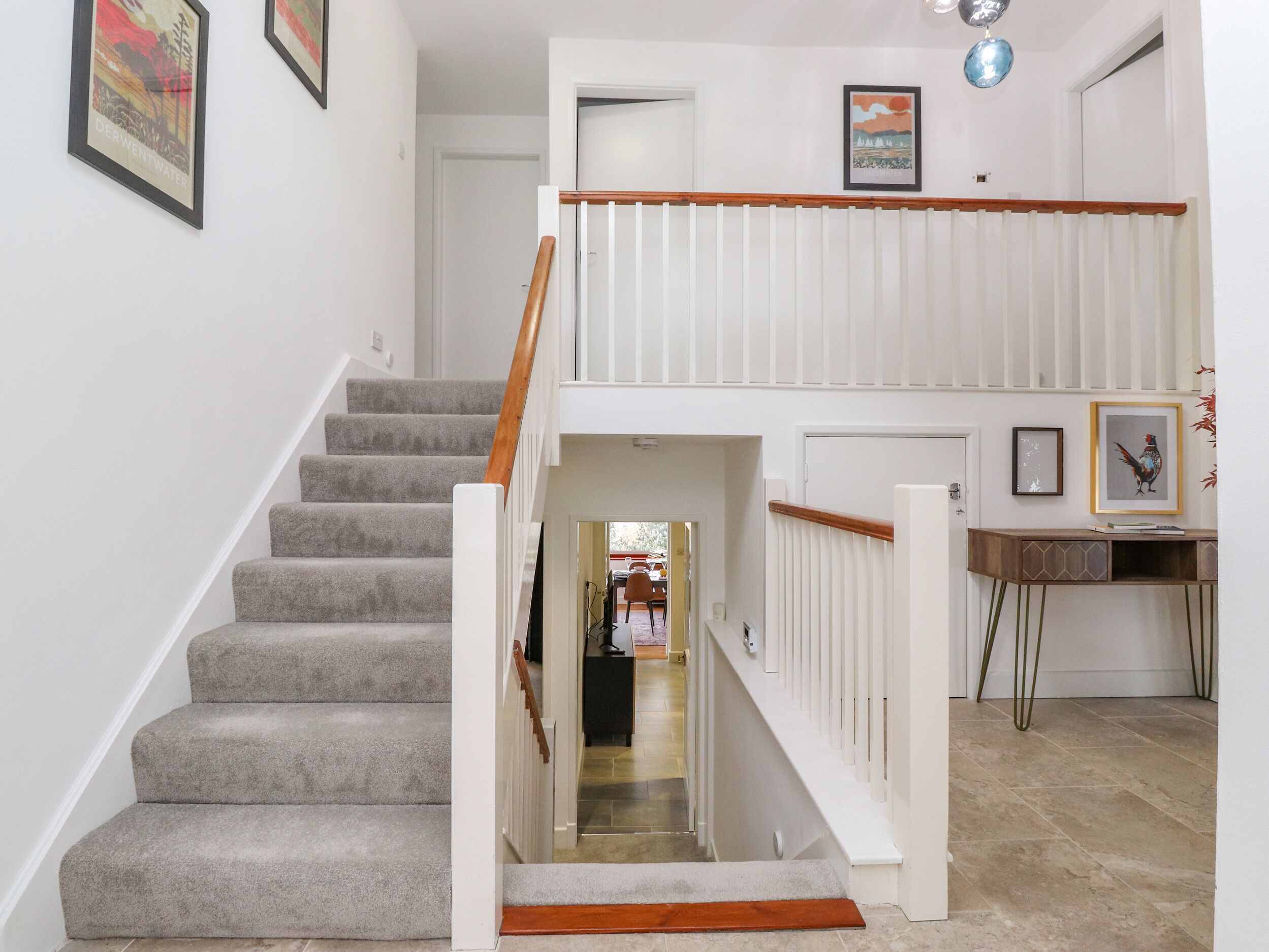 A staircase with a wooden handrail and carpeted steps leading to a landing with a white railing.