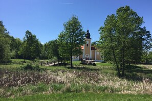 En byggnad med ett torn, omgiven av träd och en gräsyta.