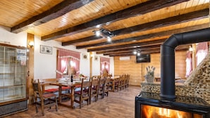 A dining area with wooden tables and chairs, a stone fireplace with a visible fire, and a television mounted on the wall. - Rustic Cottage With Heated Pool, Velika Buna, Croatia (Velika Buna)