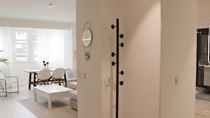 A modern living room with a dining area, a large mirror, and a black coat rack. - Brand new 2 bedroom apartment by RIO 2 and Matadero (Madrid)
