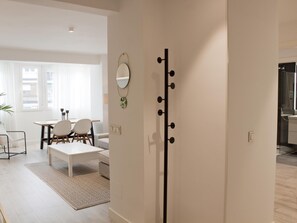 A modern living room with a dining area, a large mirror, and a black coat rack.