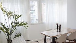 A modern dining area with a wooden table, white chairs, and a potted plant. - Brand new 2 bedroom apartment by RIO 2 and Matadero (Madrid)